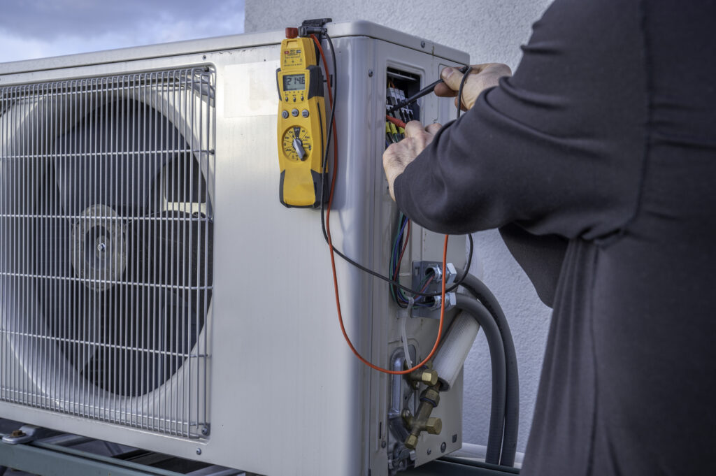 HVAC 911 | HVAC Contractor Referral Service | HVAC Service Tech Repairing A Heat Pump | Heat Pump Repair, Installation, Maintenance
